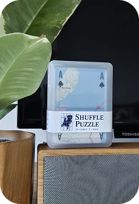 The Shuffle Puzzle deck on a speaker beside a green plant